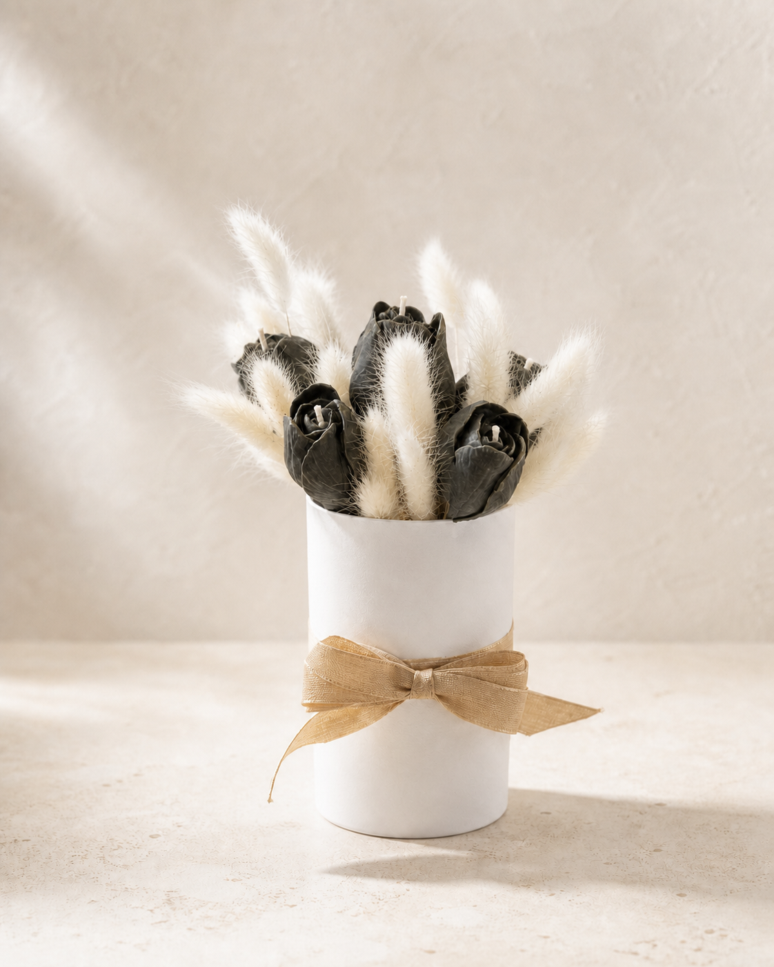 Charcoal sculptural tulip candles and ivory bunny tails in a white vase with gold ribbon
