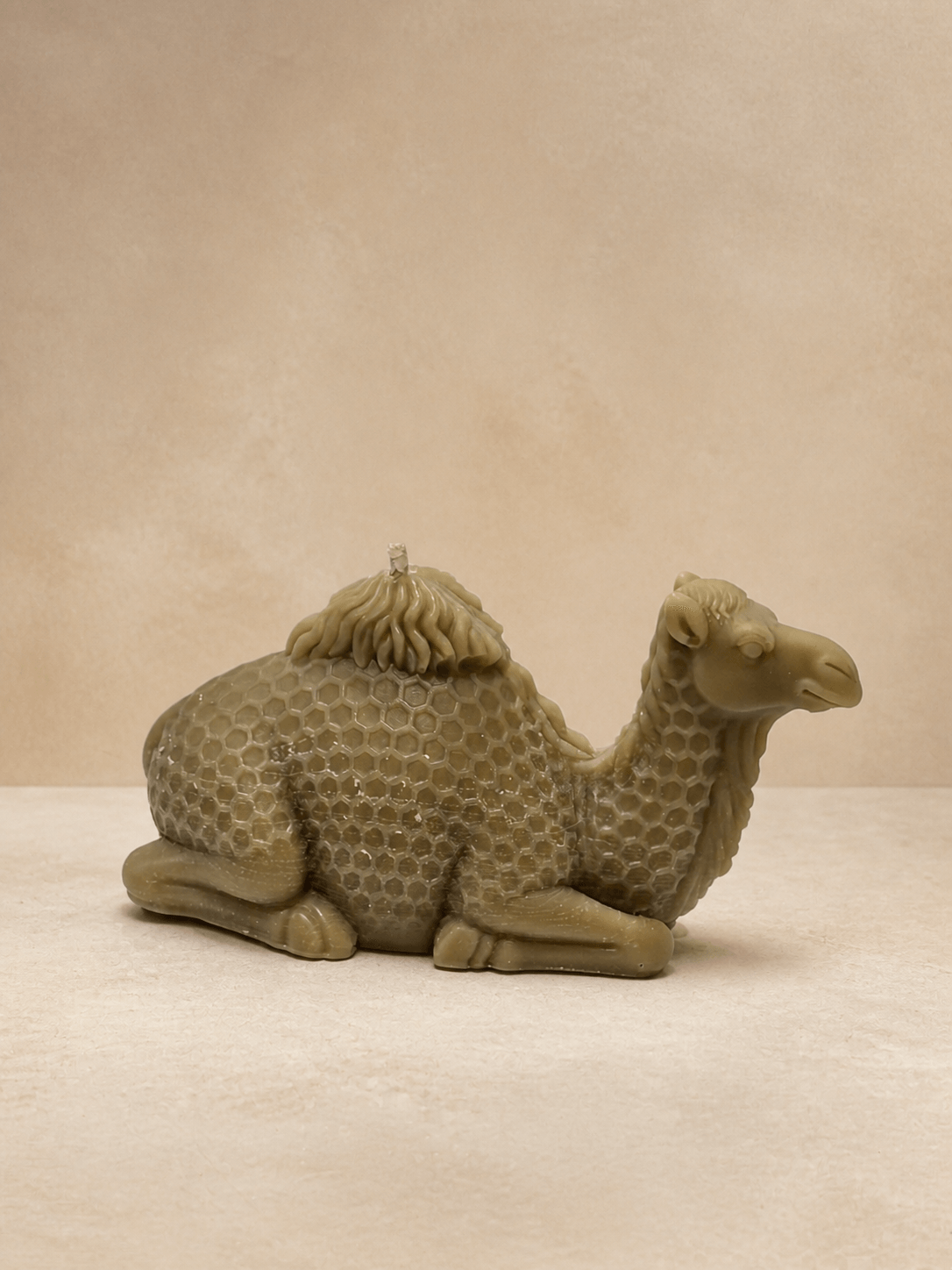 Taupe camel sculptural candle with honeycomb detailing in a warm desert-inspired studio setting